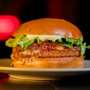 A close-up of a crispy chicken burger with lettuce and mayonnaise on a plate.