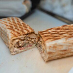Close-up of a freshly grilled shawarma wrap halved to reveal its appetizing ingredients.